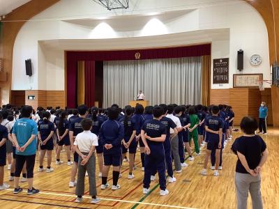6年生後方からステージ上の教頭を見る