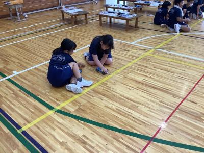 輪ゴム車を引き絞る距離を測る児童