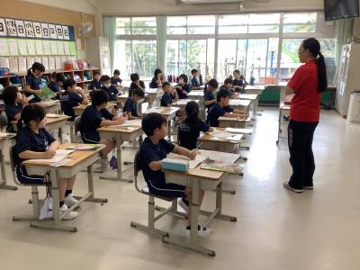 机の位置で立って発表する児童