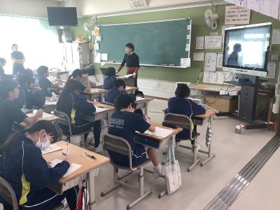 大学教授の話をメモしながら聞く5年生