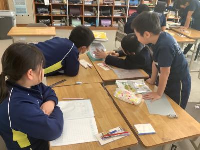 計りでノートや教科書の重さを量る3年生