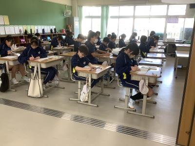 授業で習った図形をはさみで切ってノートに貼る6年生