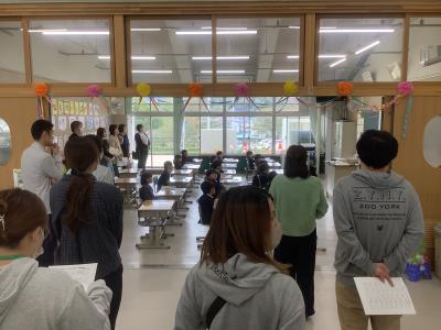 1年生の教室を右側から撮った写真です。保護者が教室の後方に並び、授業の様子を見守っています。