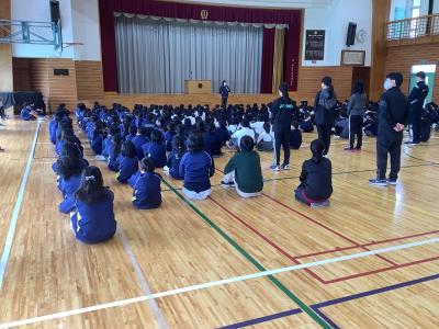 児童の前で話をする生徒指導の先生です。座っている児童越しに撮った写真です。