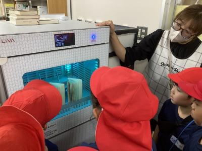 返却図書を消毒する機会を見学する児童