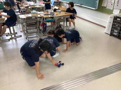 電地ボックスを自動車につなげる児童