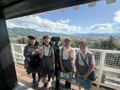 鶴ヶ城からの景色を背景に記念撮影する6年生